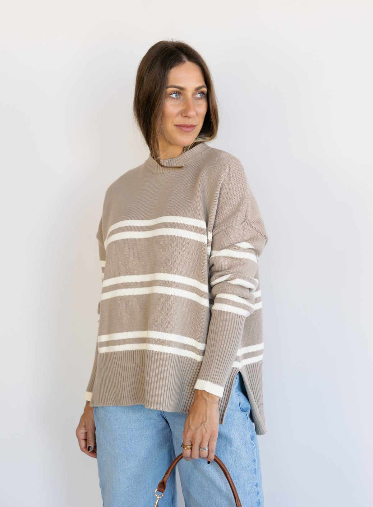 Woman wearing the Lucille Sweater in Taupe, an oversized taupe and cream striped crewneck sweater