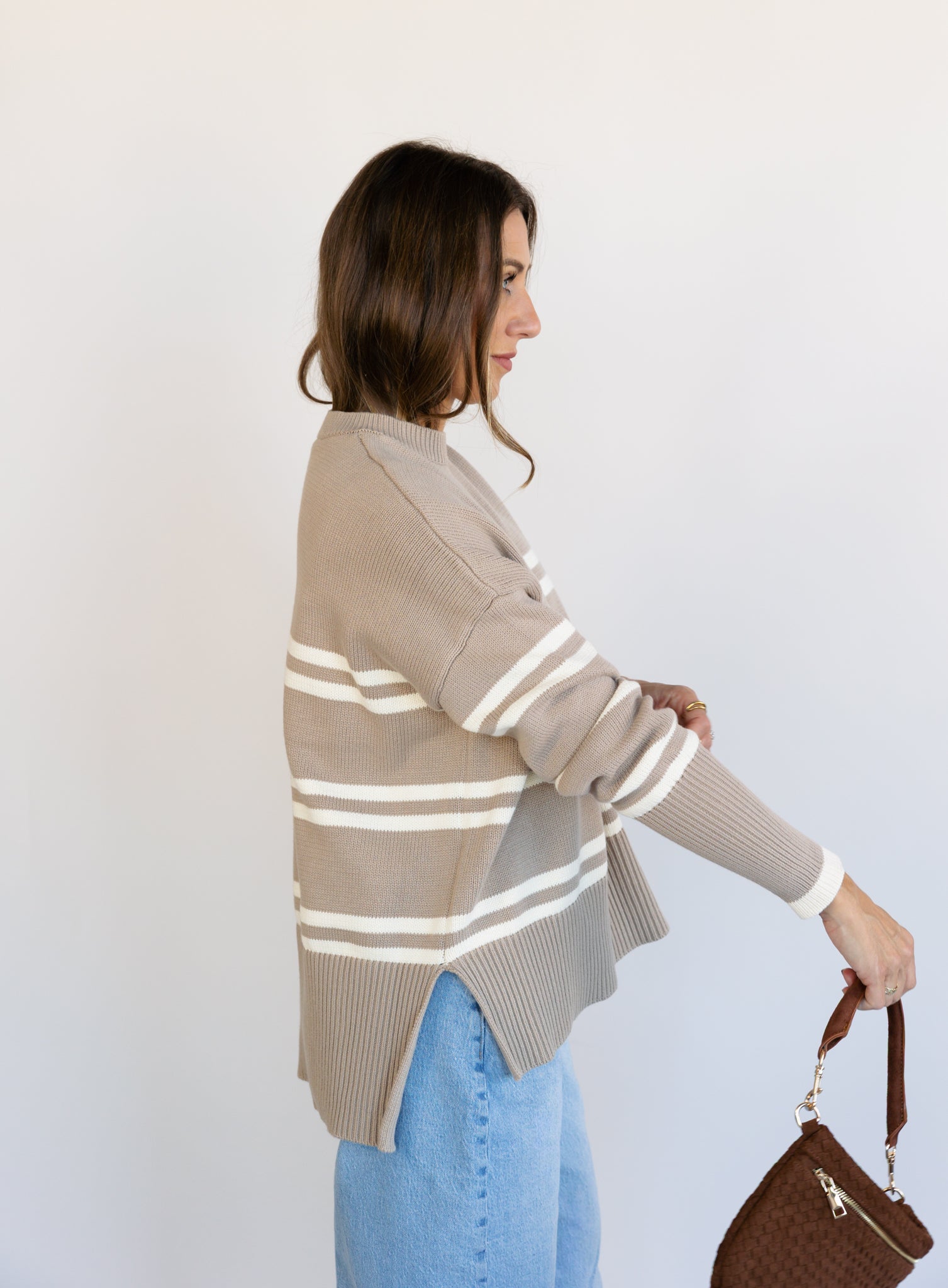 Woman wearing the Lucille Sweater in Taupe, an oversized taupe and cream striped crewneck sweater