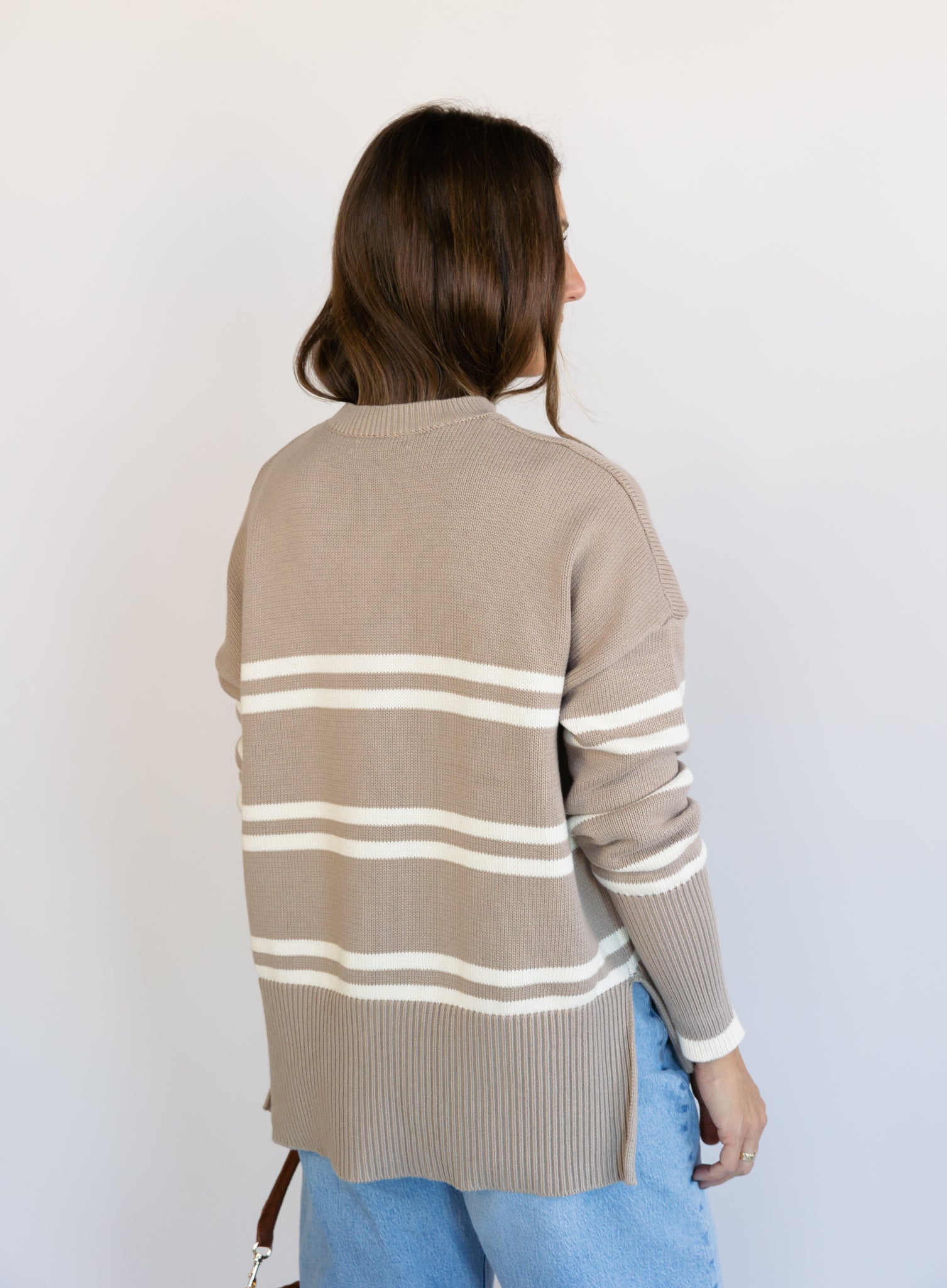 Woman wearing the Lucille Sweater in Taupe, an oversized taupe and cream striped crewneck sweater
