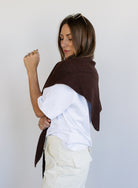 Woman wearing the Wrenley Warm Shawl Scarf in Brown, a chocolate brown knit triangle shawl