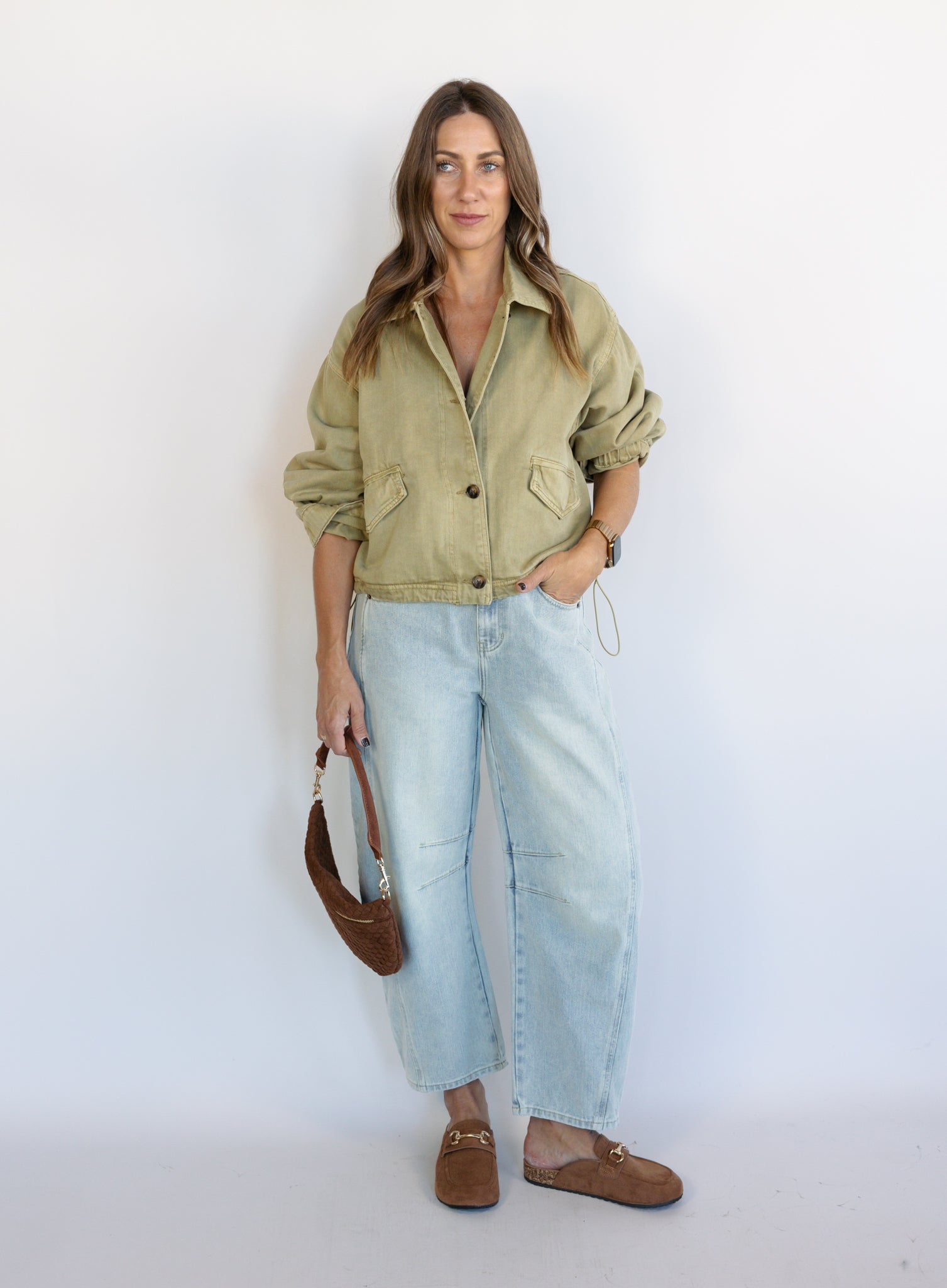 Woman wearing the Zuri Denim Jacket, a light olive cropped cotton twill utility jacket