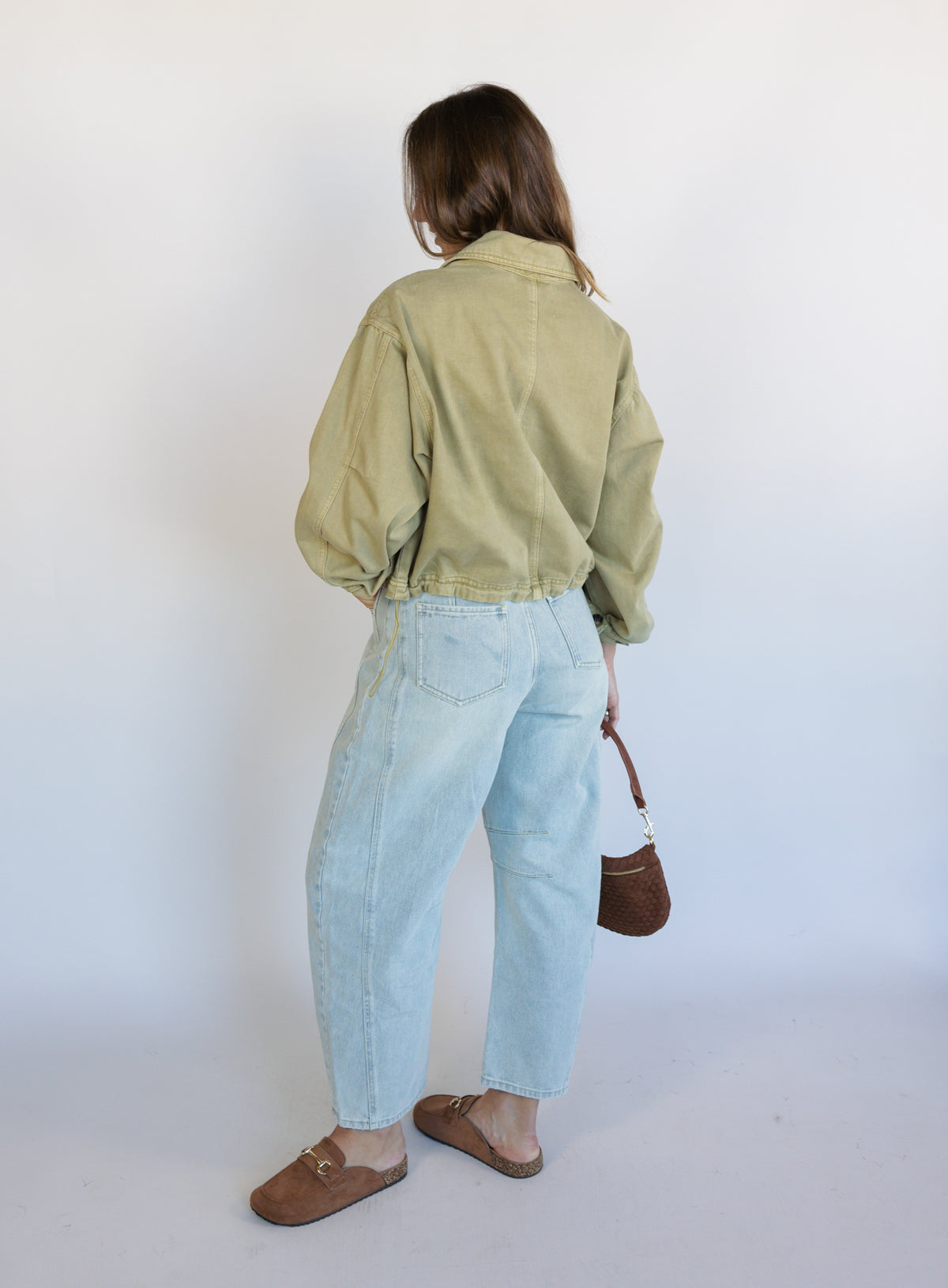 Woman wearing the Zuri Denim Jacket, a light olive cropped cotton twill utility jacket