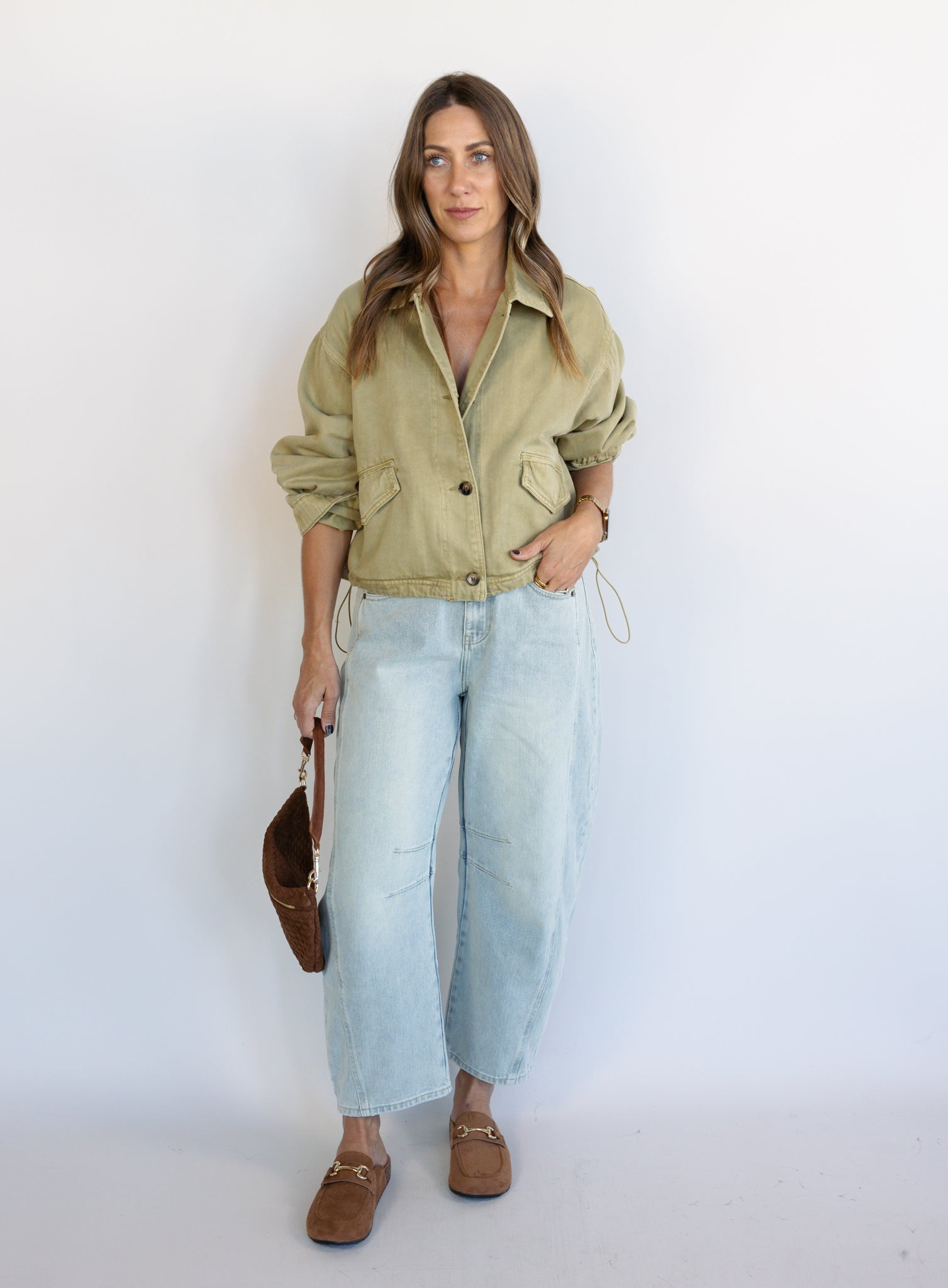Woman wearing the Zuri Denim Jacket, a light olive cropped cotton twill utility jacket