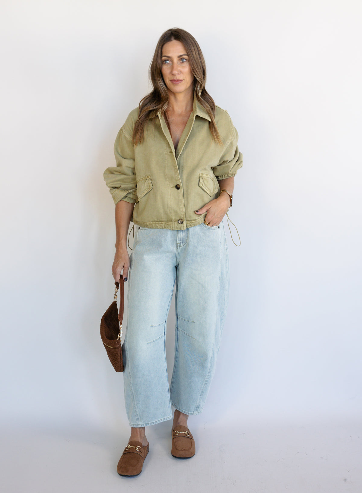 Woman wearing the Zuri Denim Jacket, a light olive cropped cotton twill utility jacket
