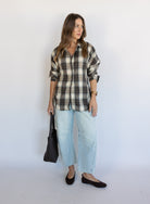 Woman wearing the Heartloom Bobbie Shirt, a black, cream and grey plaid oversized button-down