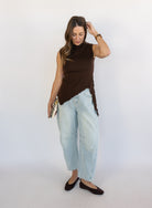 Woman wearing the Coralie Ruffle Trim Sweater Tank, a chocolate brown mock neck knit tank with a ruffle hem