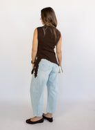 Woman wearing the Coralie Ruffle Trim Sweater Tank, a chocolate brown mock neck knit tank with a ruffle hem