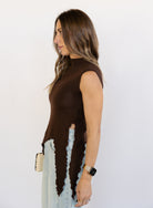 Woman wearing the Coralie Ruffle Trim Sweater Tank, a chocolate brown mock neck knit tank with a ruffle hem