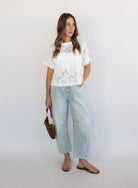 Woman wearing the Lillia Lace Floral Tee, a sheer white mesh tee with floral embroidery