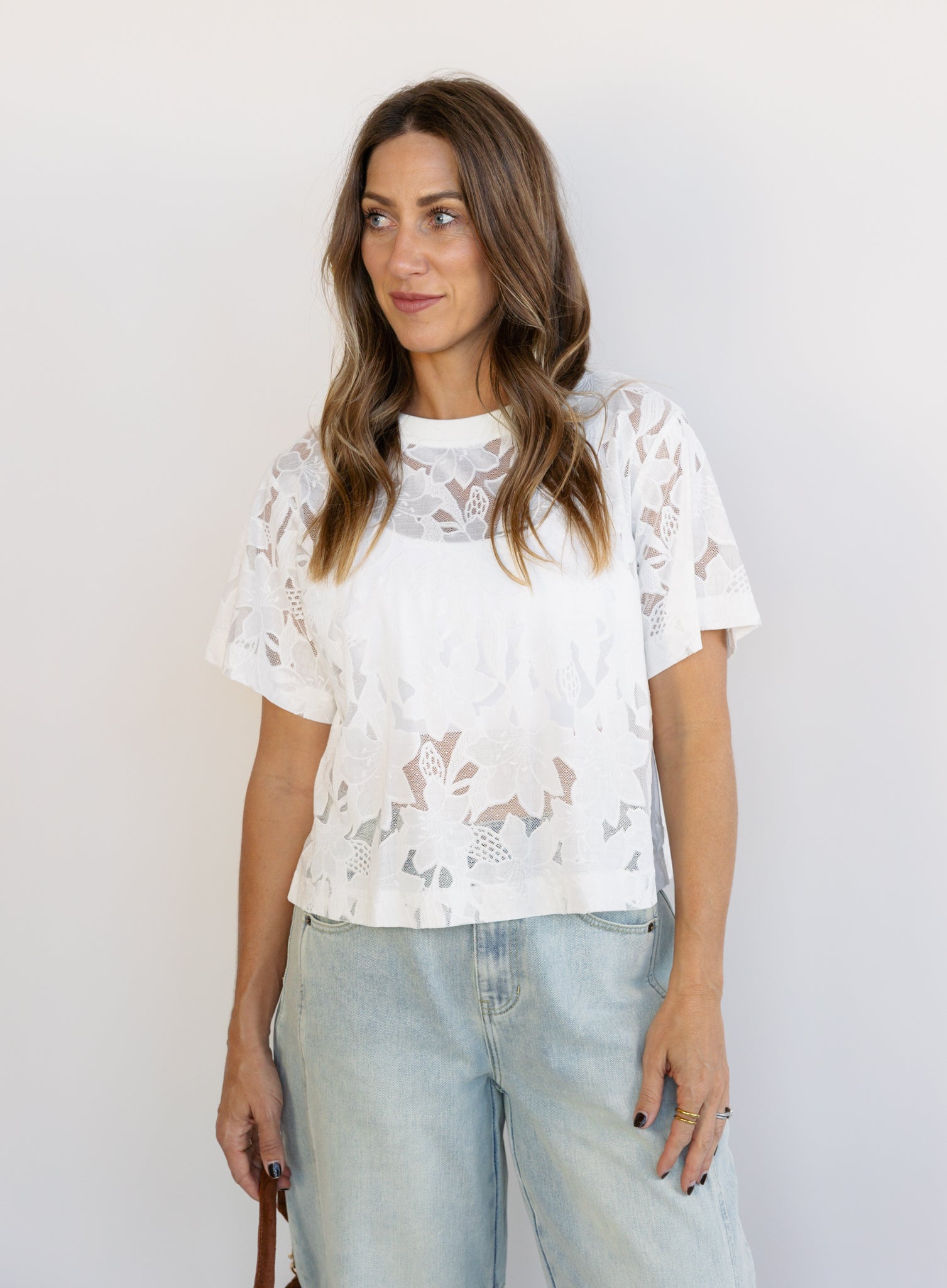 Woman wearing the Lillia Lace Floral Tee, a sheer white mesh tee with floral embroidery