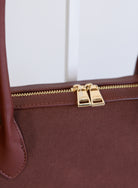 Jonava Suede Bag in Garnet, a deep garnet elongated suede shoulder bag with gold zipper pulls