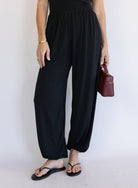 Woman wearing the Azalea Balloon Pants, black lightweight balloon-leg pants with gathered ankle cuffs