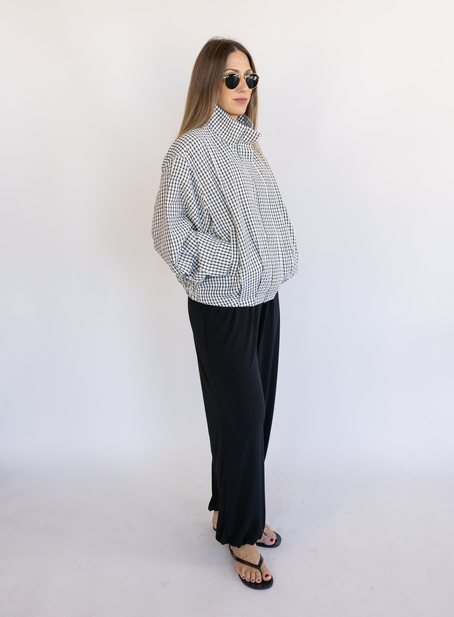 Woman wearing the Calliope Funnel Neck Bomber Jacket, a black and white gingham zip-up bomber