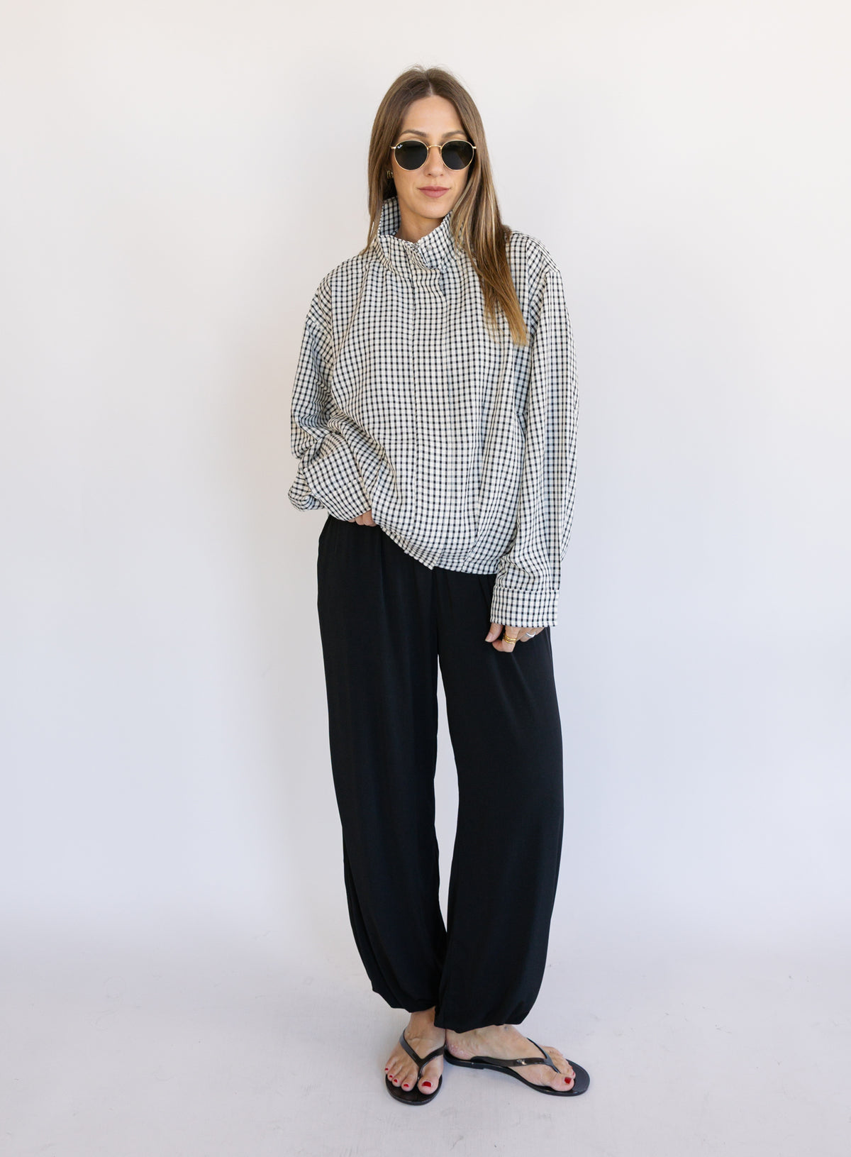 Woman wearing the Calliope Funnel Neck Bomber Jacket, a black and white gingham zip-up bomber