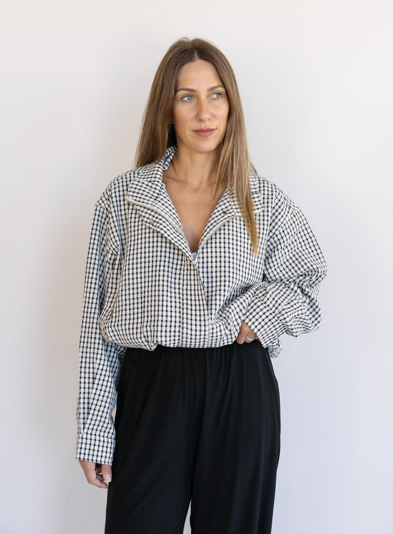 Woman wearing the Calliope Funnel Neck Bomber Jacket, a black and white gingham zip-up bomber