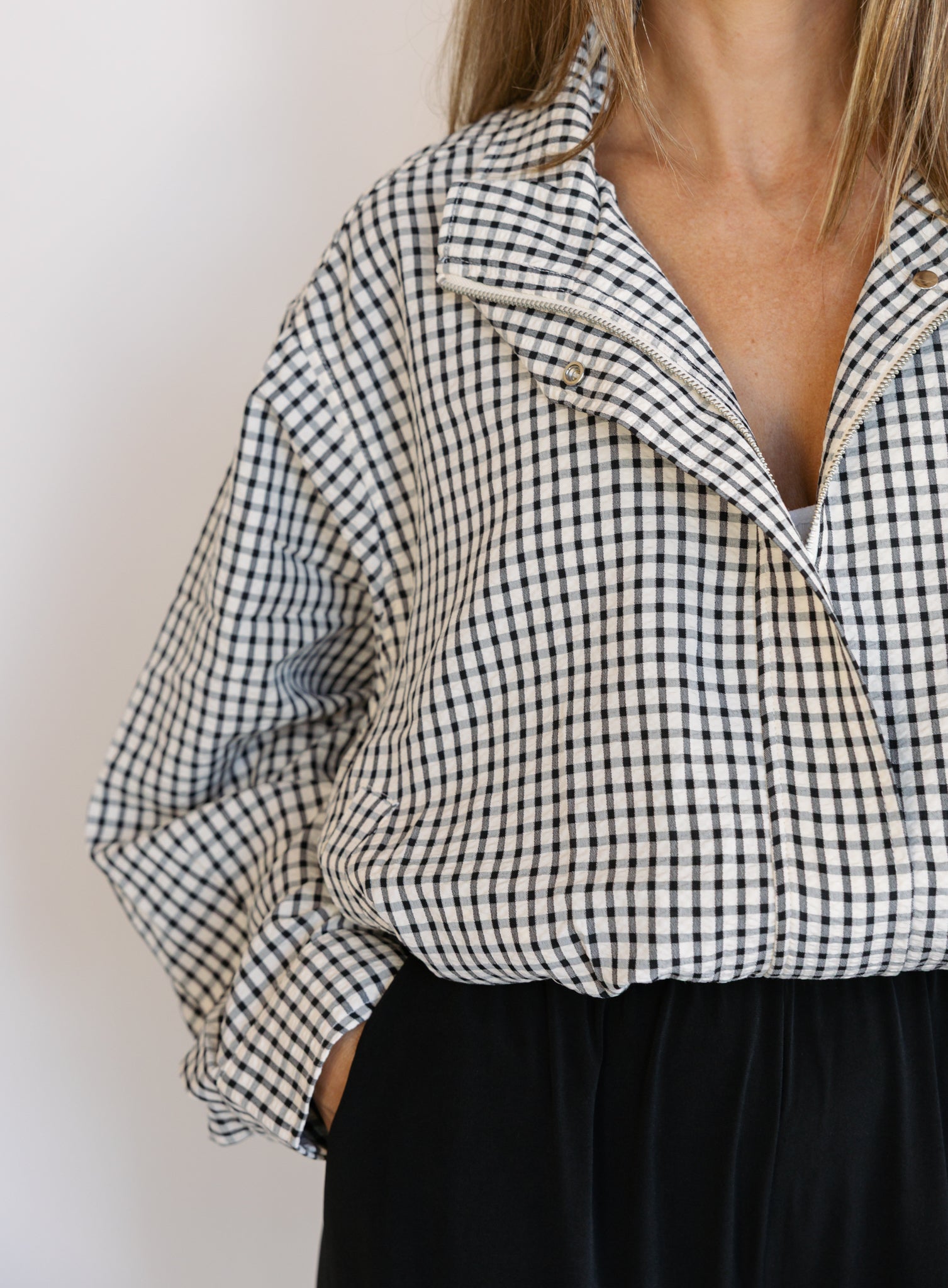 Woman wearing the Calliope Funnel Neck Bomber Jacket, a black and white gingham zip-up bomber