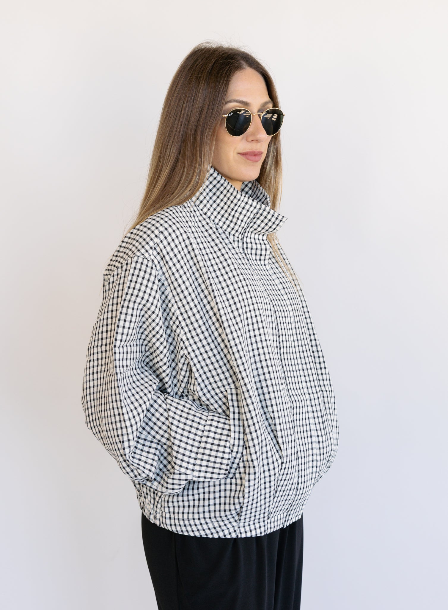 Woman wearing the Calliope Funnel Neck Bomber Jacket, a black and white gingham zip-up bomber