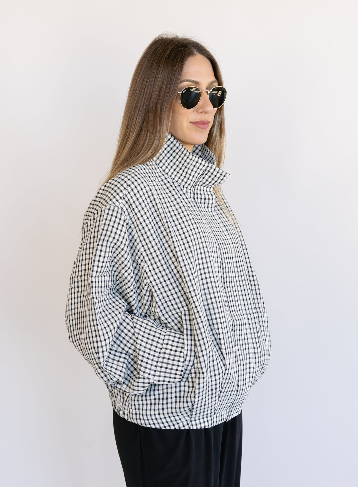 Woman wearing the Calliope Funnel Neck Bomber Jacket, a black and white gingham zip-up bomber
