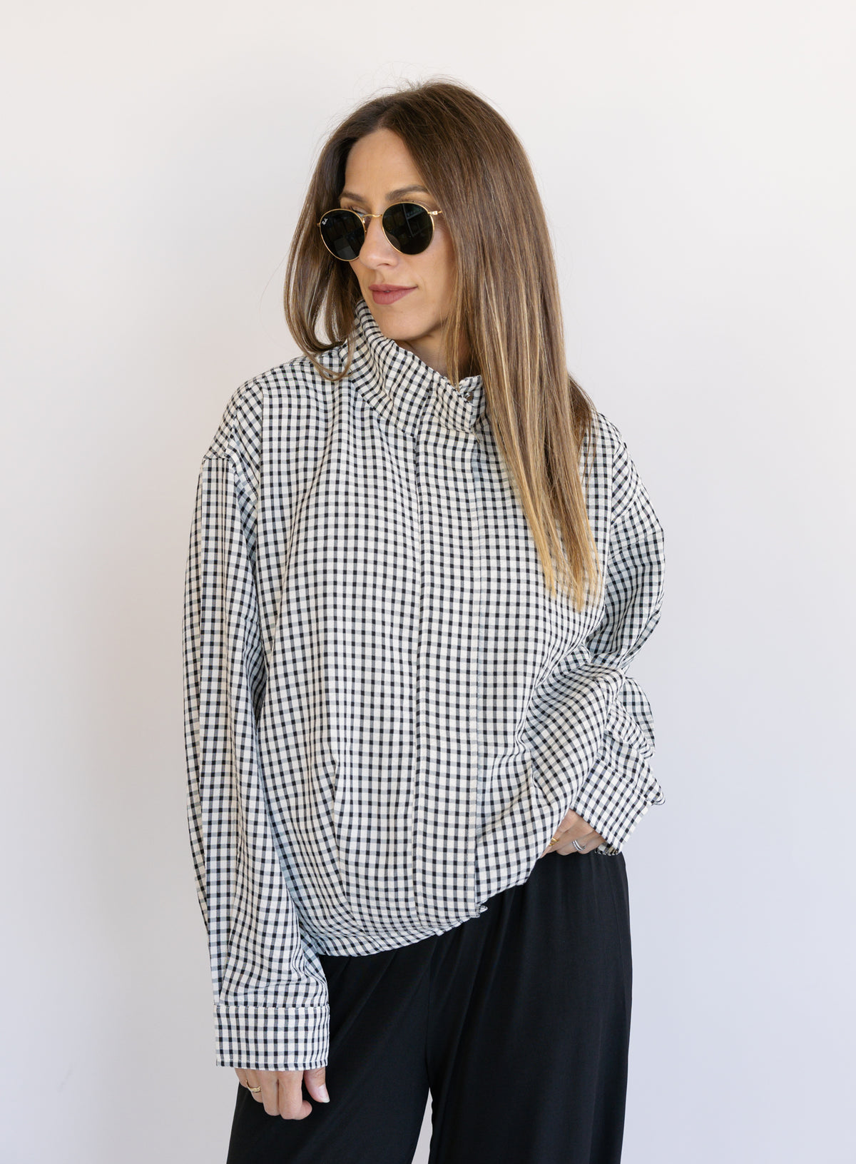 Woman wearing the Calliope Funnel Neck Bomber Jacket, a black and white gingham zip-up bomber