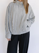 Woman wearing the Calliope Funnel Neck Bomber Jacket, a black and white gingham zip-up bomber
