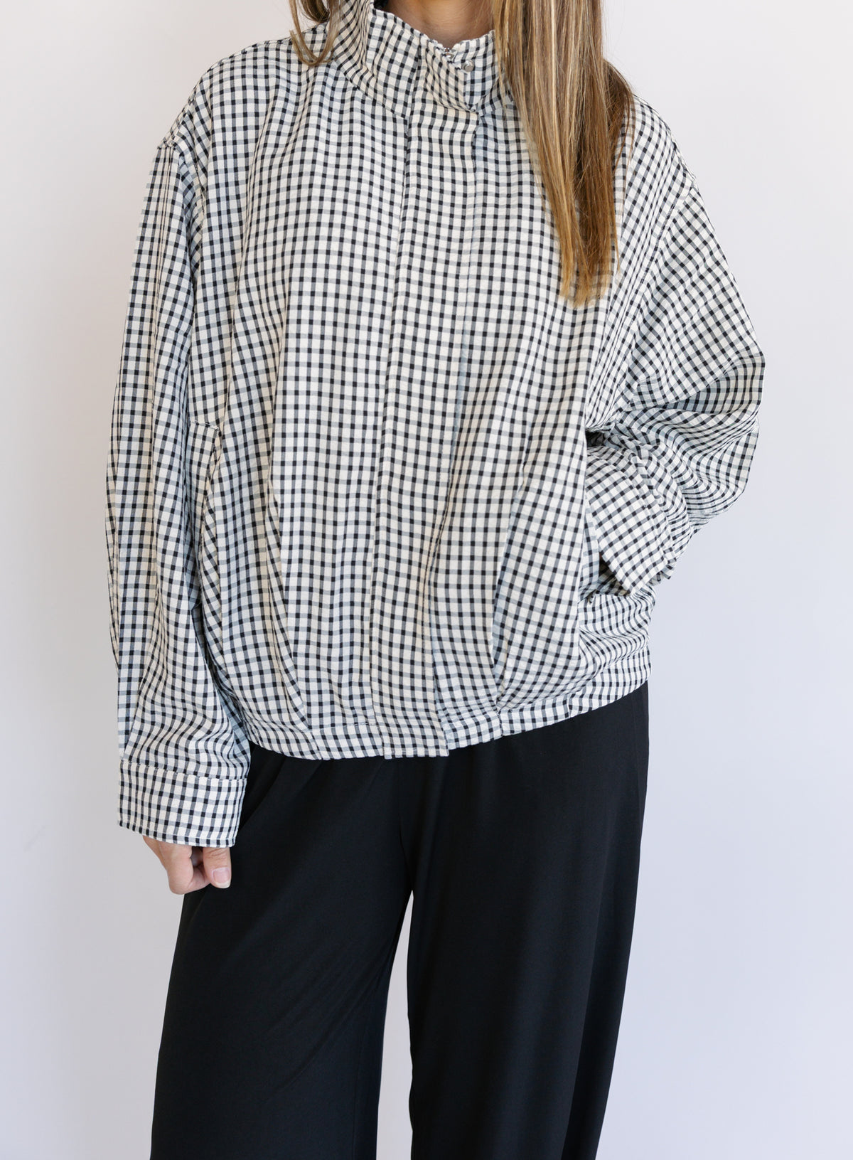 Woman wearing the Calliope Funnel Neck Bomber Jacket, a black and white gingham zip-up bomber