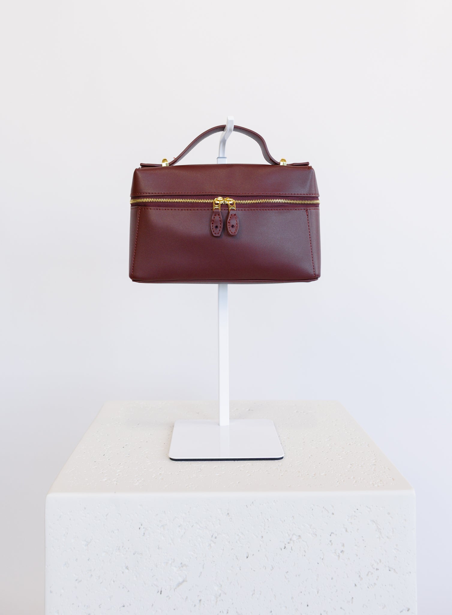 Sabine Bag, a burgundy boxy top-handle bag with gold hardware and a crossbody strap