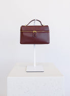 Sabine Bag, a burgundy boxy top-handle bag with gold hardware and a crossbody strap
