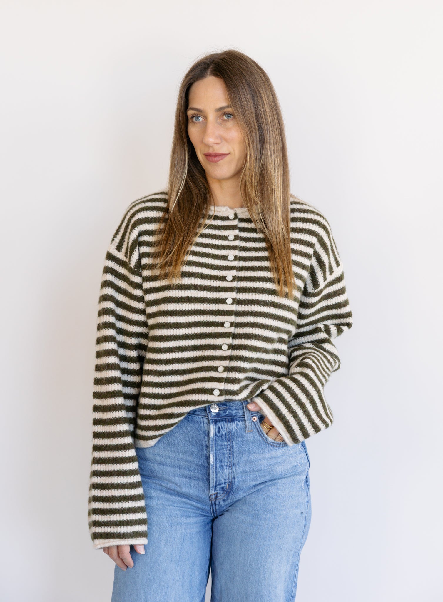 Woman wearing the Marlowe Striped Cardigan, an olive and cream striped button-front cardigan