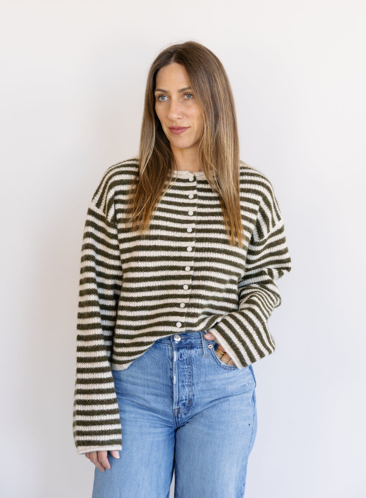 Woman wearing the Marlowe Striped Cardigan, an olive and cream striped button-front cardigan