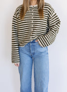 Woman wearing the Marlowe Striped Cardigan, an olive and cream striped button-front cardigan