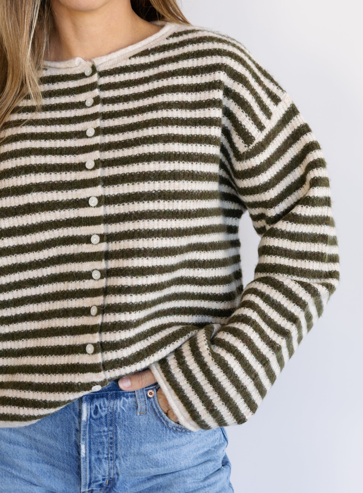 Woman wearing the Marlowe Striped Cardigan, an olive and cream striped button-front cardigan