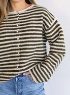 Woman wearing the Marlowe Striped Cardigan, an olive and cream striped button-front cardigan