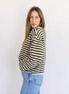 Woman wearing the Marlowe Striped Cardigan, an olive and cream striped button-front cardigan