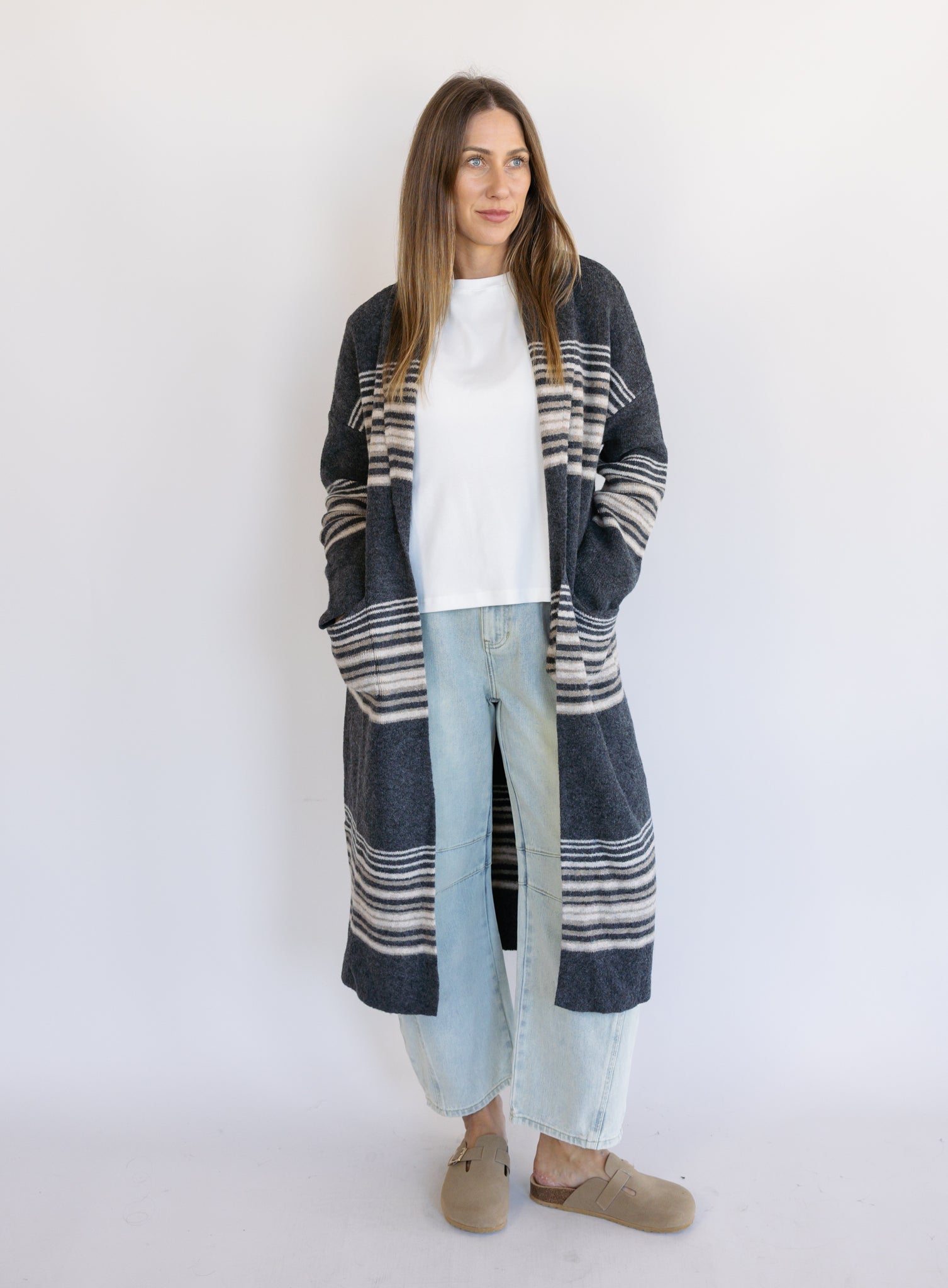 Woman wearing the Linnea Striped Sweater Coat, a long charcoal knit coat with cream and taupe stripes