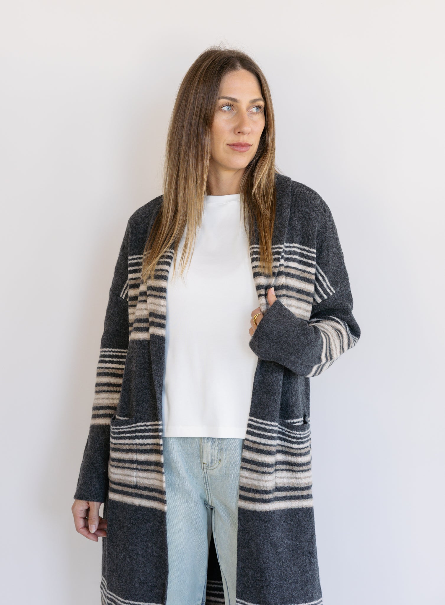 Woman wearing the Linnea Striped Sweater Coat, a long charcoal knit coat with cream and taupe stripes