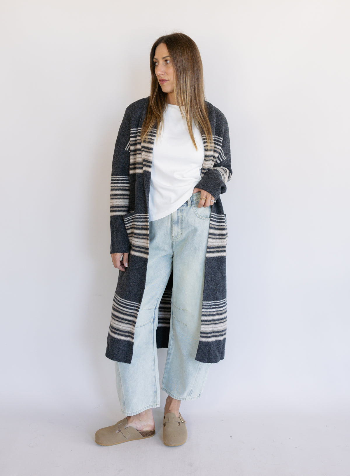 Woman wearing the Linnea Striped Sweater Coat, a long charcoal knit coat with cream and taupe stripes