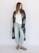 Woman wearing the Linnea Striped Sweater Coat, a long charcoal knit coat with cream and taupe stripes