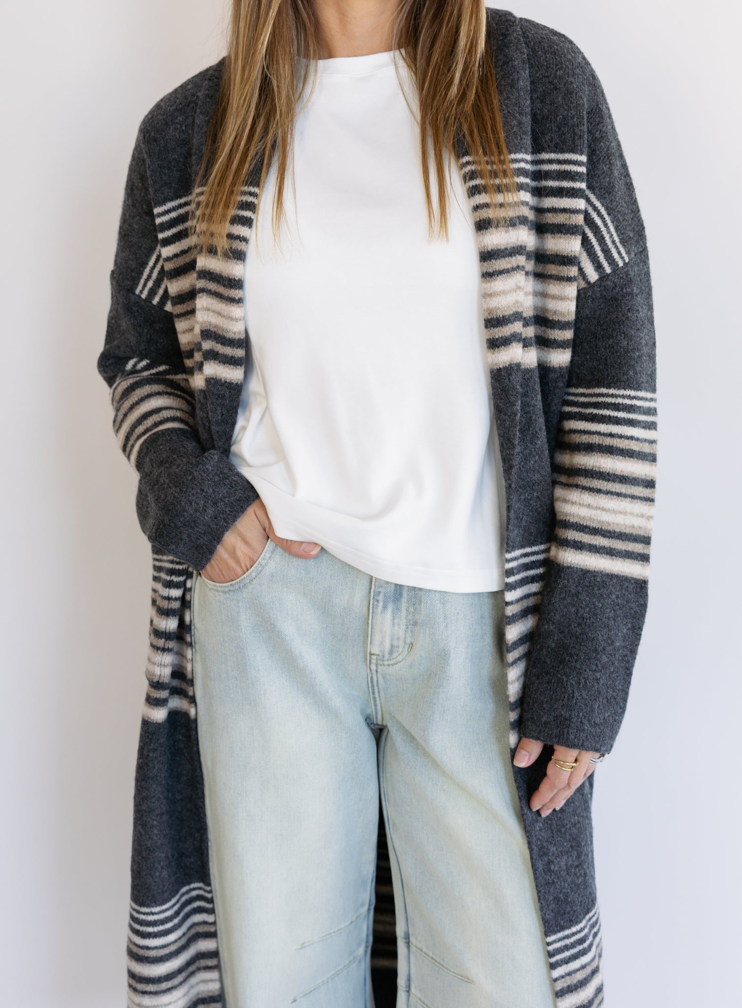 Woman wearing the Linnea Striped Sweater Coat, a long charcoal knit coat with cream and taupe stripes