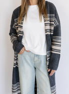 Woman wearing the Linnea Striped Sweater Coat, a long charcoal knit coat with cream and taupe stripes