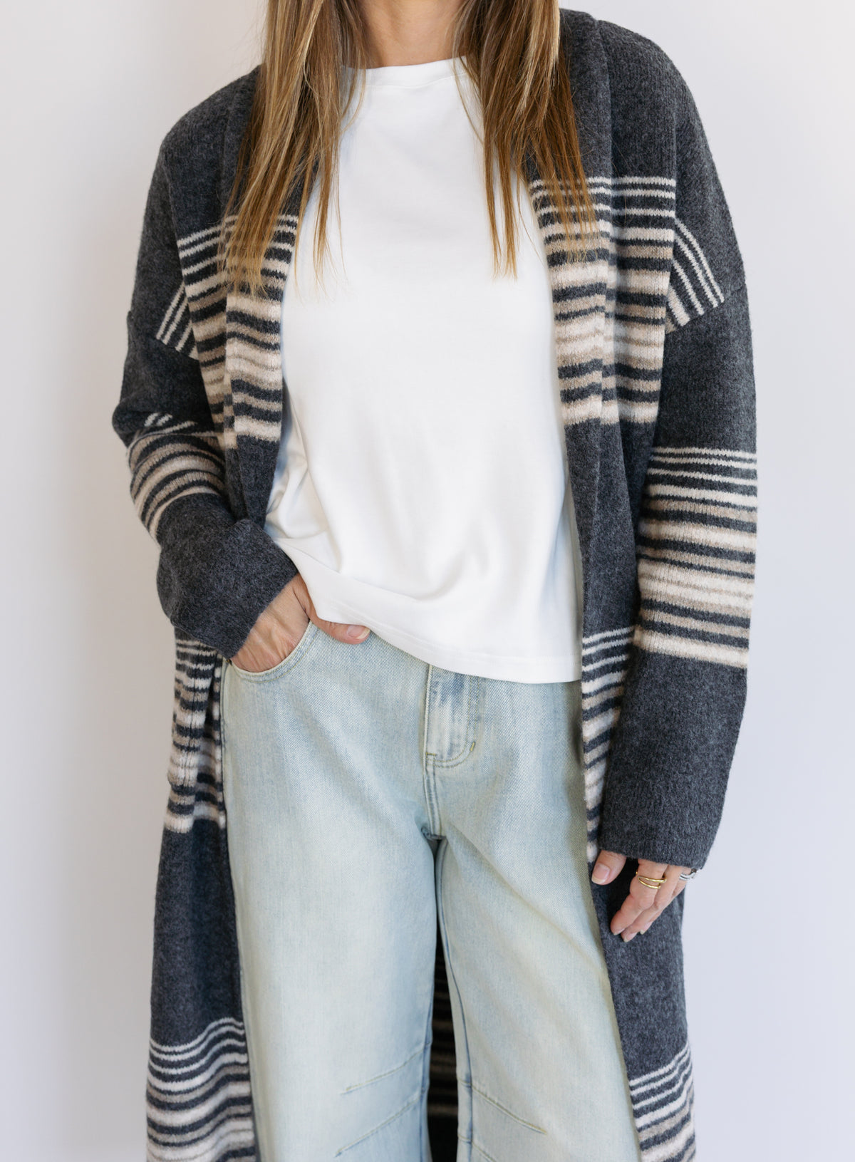 Woman wearing the Linnea Striped Sweater Coat, a long charcoal knit coat with cream and taupe stripes
