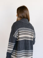 Woman wearing the Linnea Striped Sweater Coat, a long charcoal knit coat with cream and taupe stripes