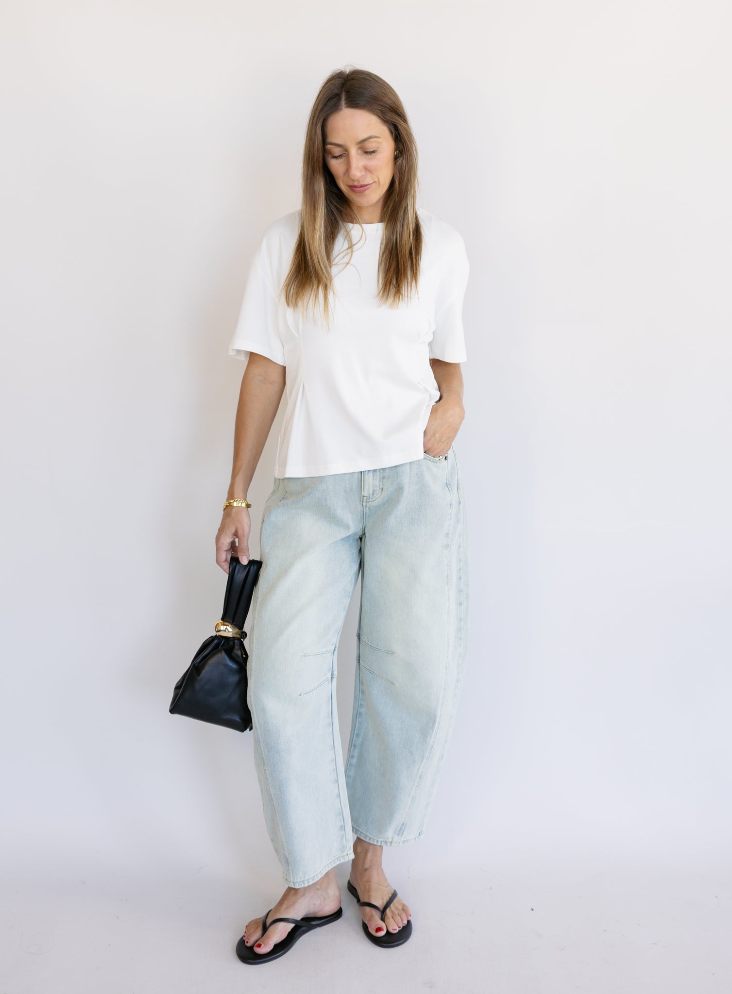 Woman wearing the Lakelyn Cinched Top, a white structured knit crewneck tee cinched at the waist