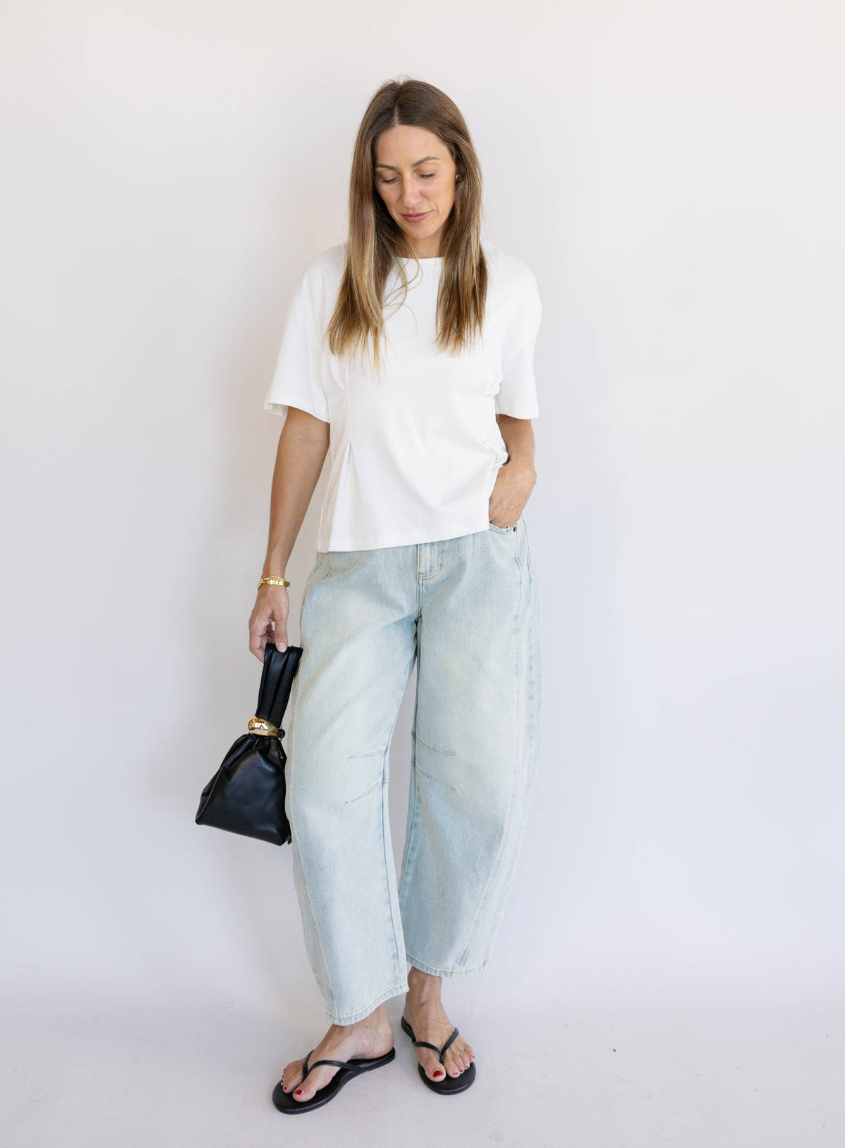 Woman wearing the Lakelyn Cinched Top, a white structured knit crewneck tee cinched at the waist