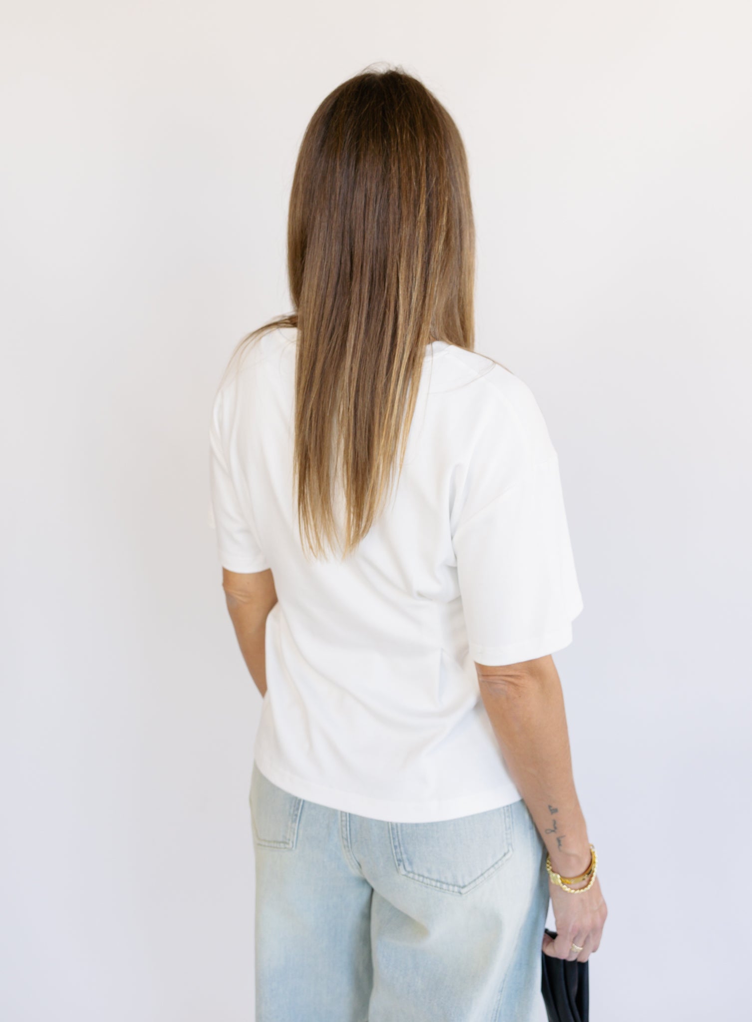 Woman wearing the Lakelyn Cinched Top, a white structured knit crewneck tee cinched at the waist