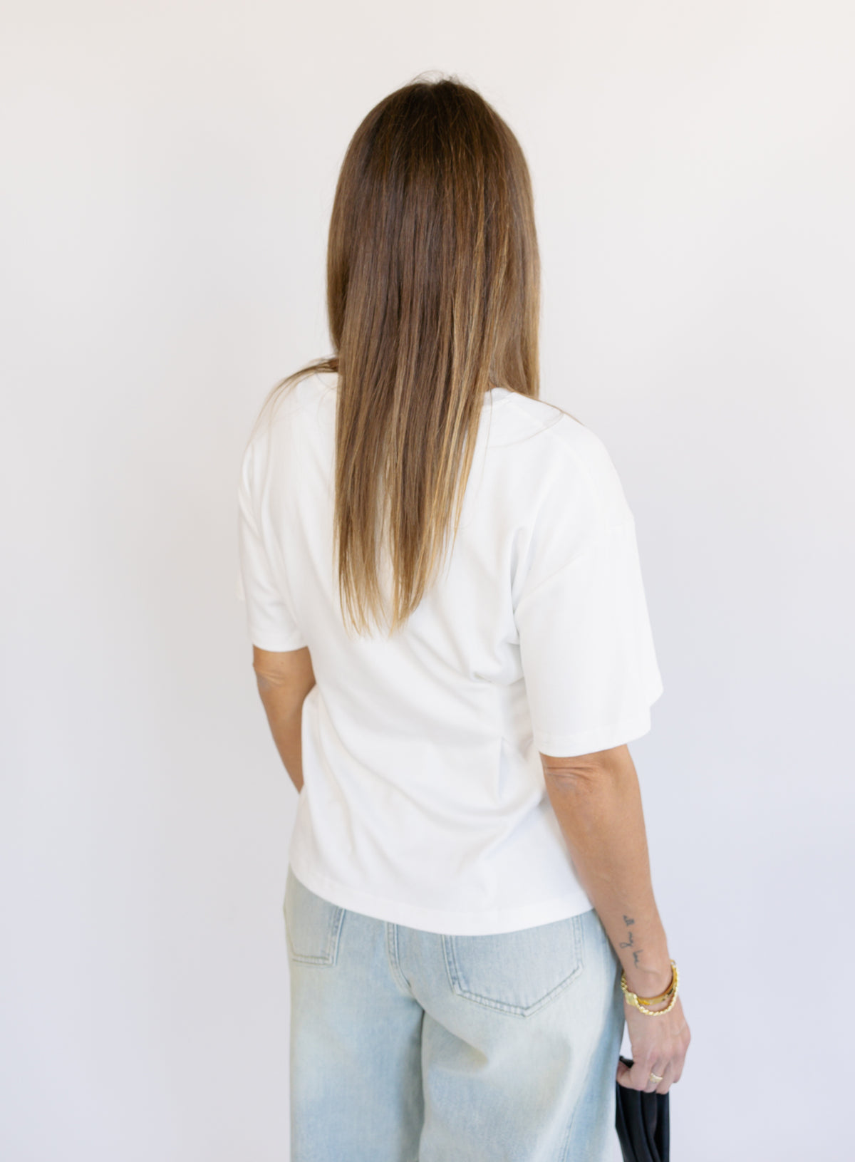 Woman wearing the Lakelyn Cinched Top, a white structured knit crewneck tee cinched at the waist