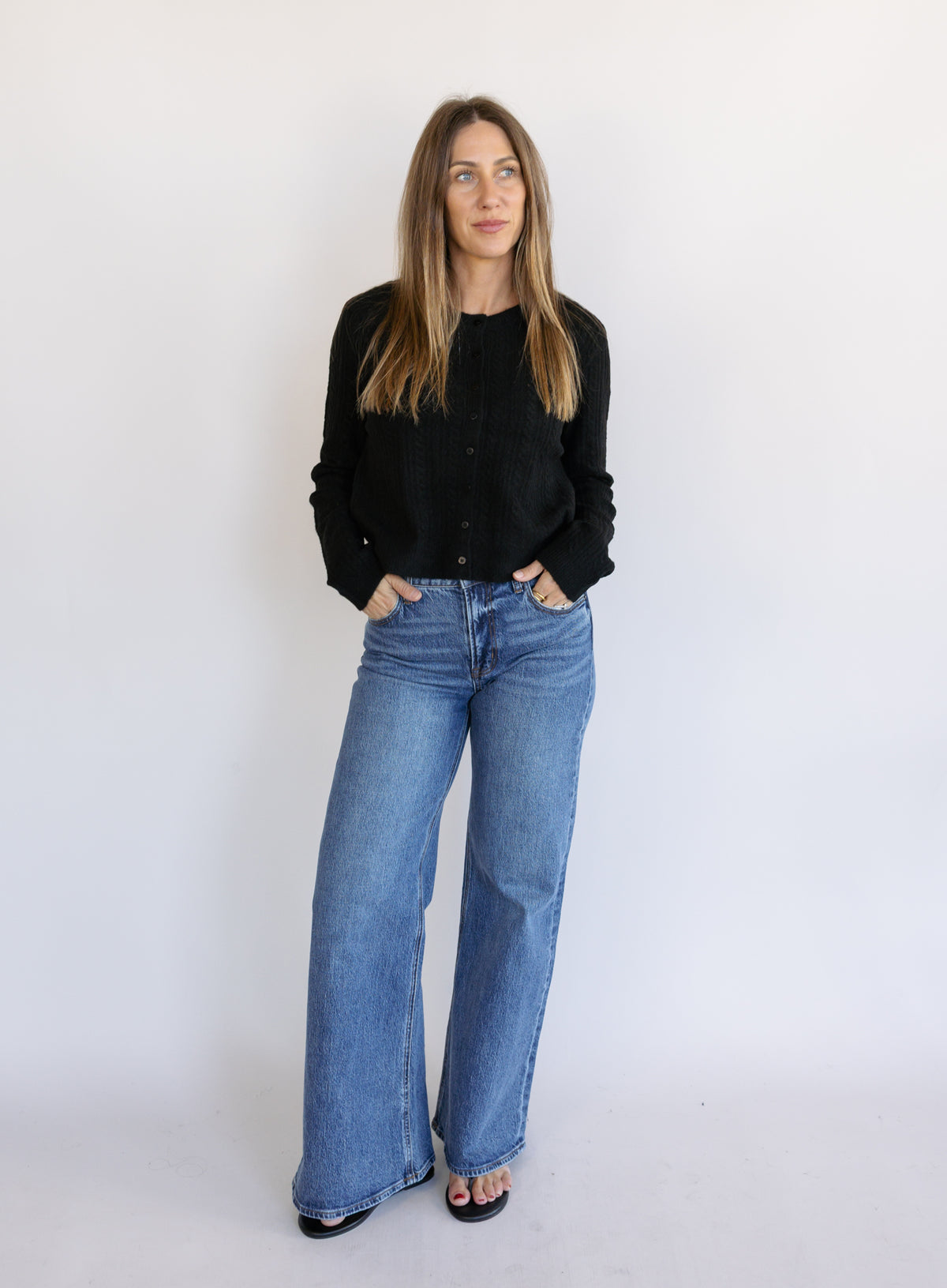 Woman wearing the Z Supply Medina Pointelle Cardigan, a black cable pointelle knit button-front cardigan