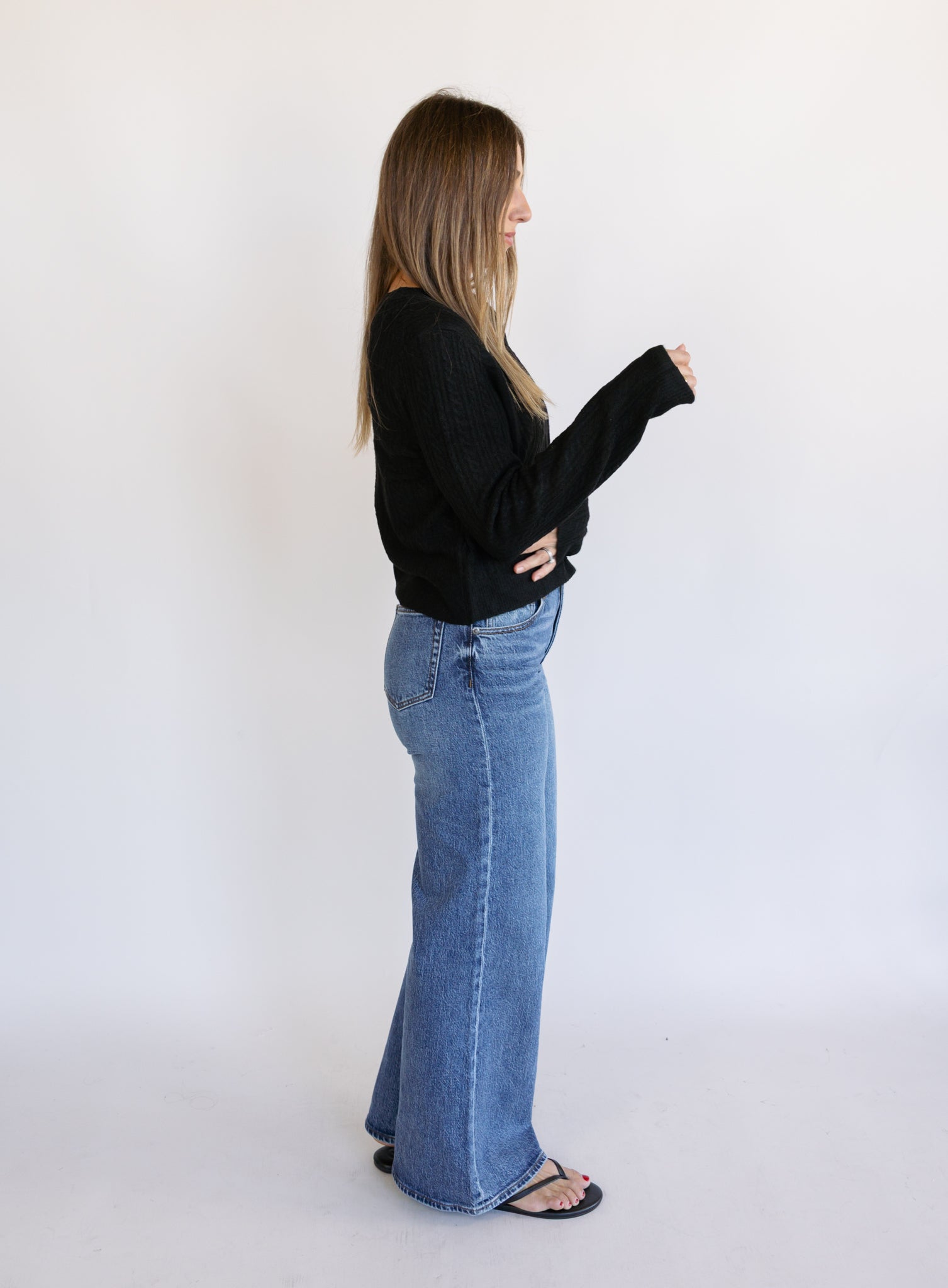 Woman wearing the Z Supply Medina Pointelle Cardigan, a black cable pointelle knit button-front cardigan