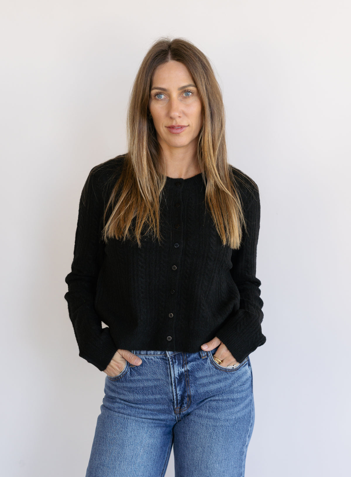 Woman wearing the Z Supply Medina Pointelle Cardigan, a black cable pointelle knit button-front cardigan