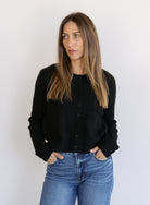 Woman wearing the Z Supply Medina Pointelle Cardigan, a black cable pointelle knit button-front cardigan