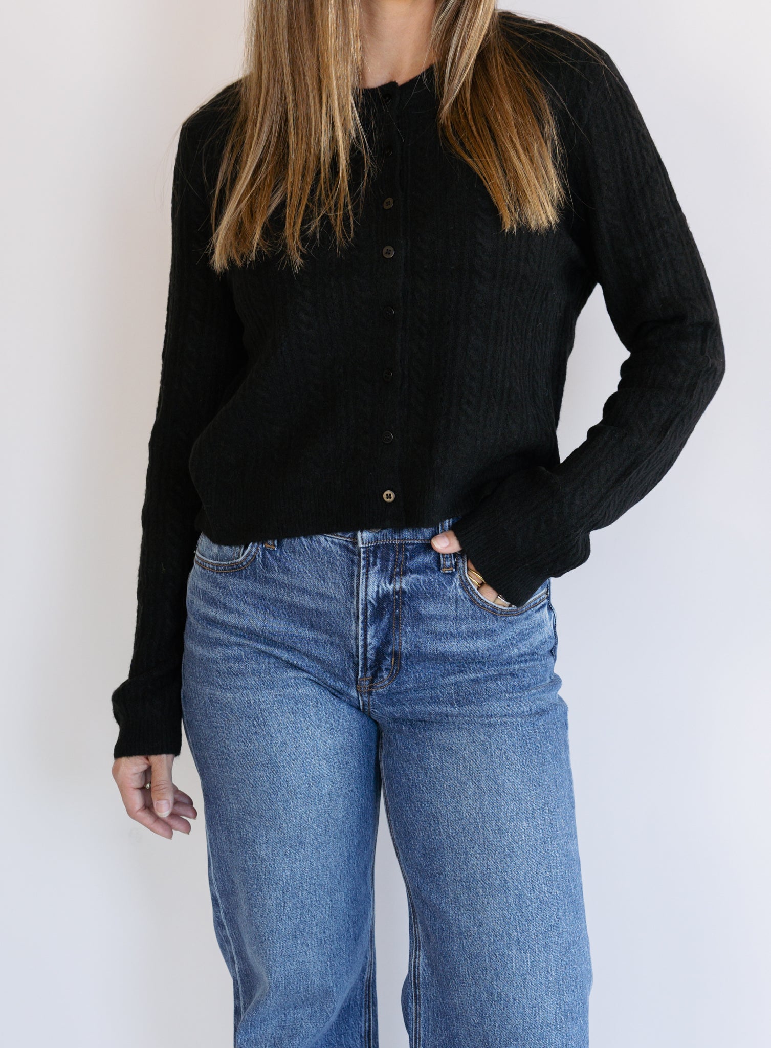Woman wearing the Z Supply Medina Pointelle Cardigan, a black cable pointelle knit button-front cardigan